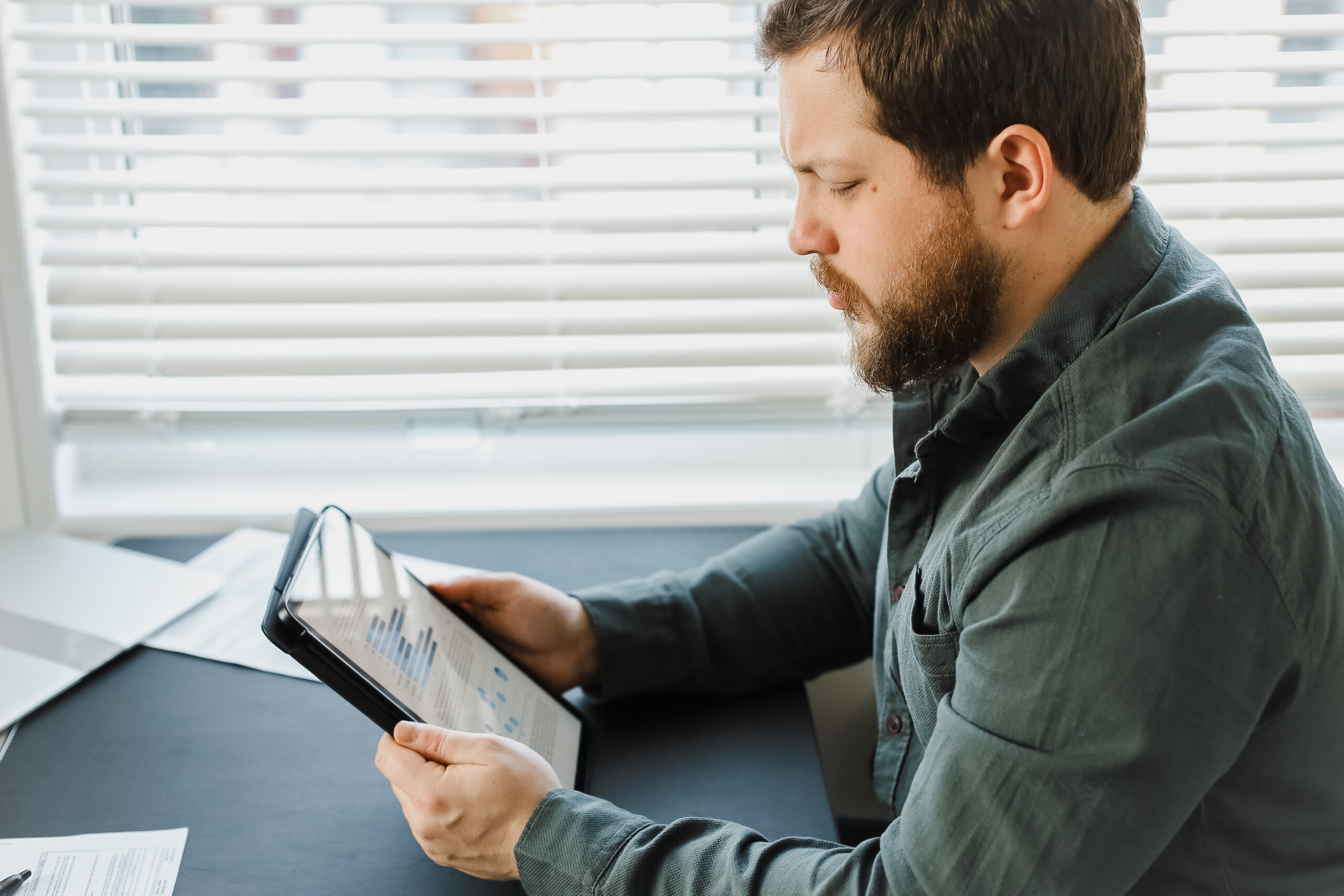 Business professional reviewing charts and performance analytics on a tablet in a modern office.